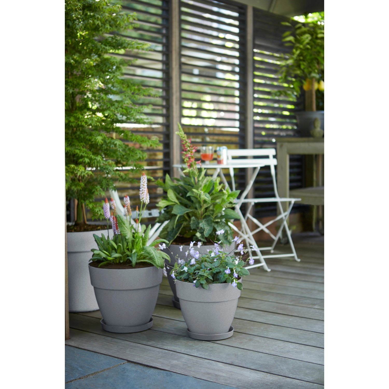 Elho Blumentopf Vibia Campana, Ø 30 cm, Living Beton, mit Pflanzen auf einer Terrasse.