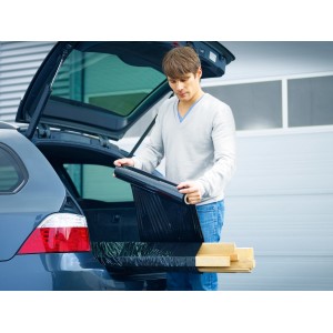 Mann verpackt Holz mit schwarzer LUX Stretchfolie im Kofferraum eines Autos.