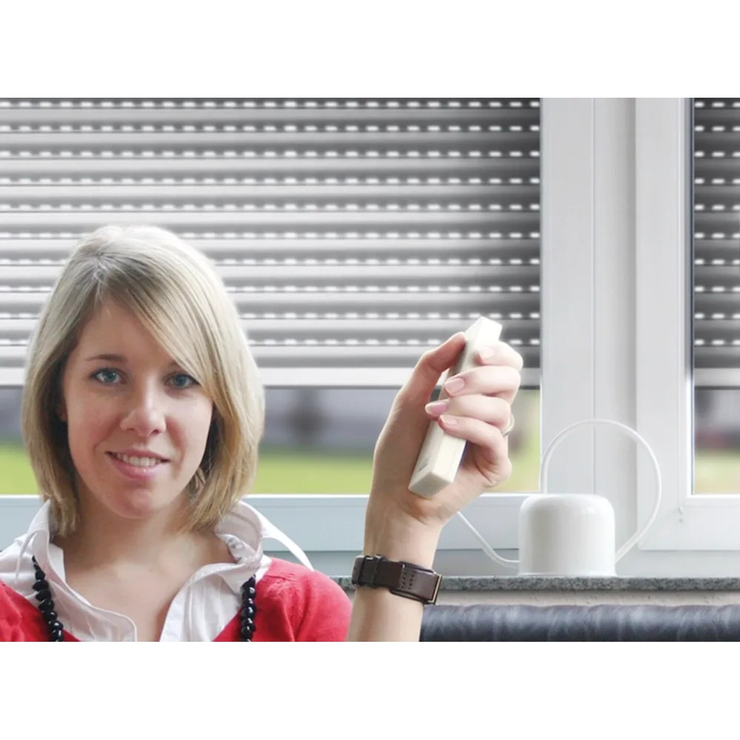 Frau bedient Schellenberg Rollladenantrieb RolloDrive 65 Premium per Funkfernbedienung.