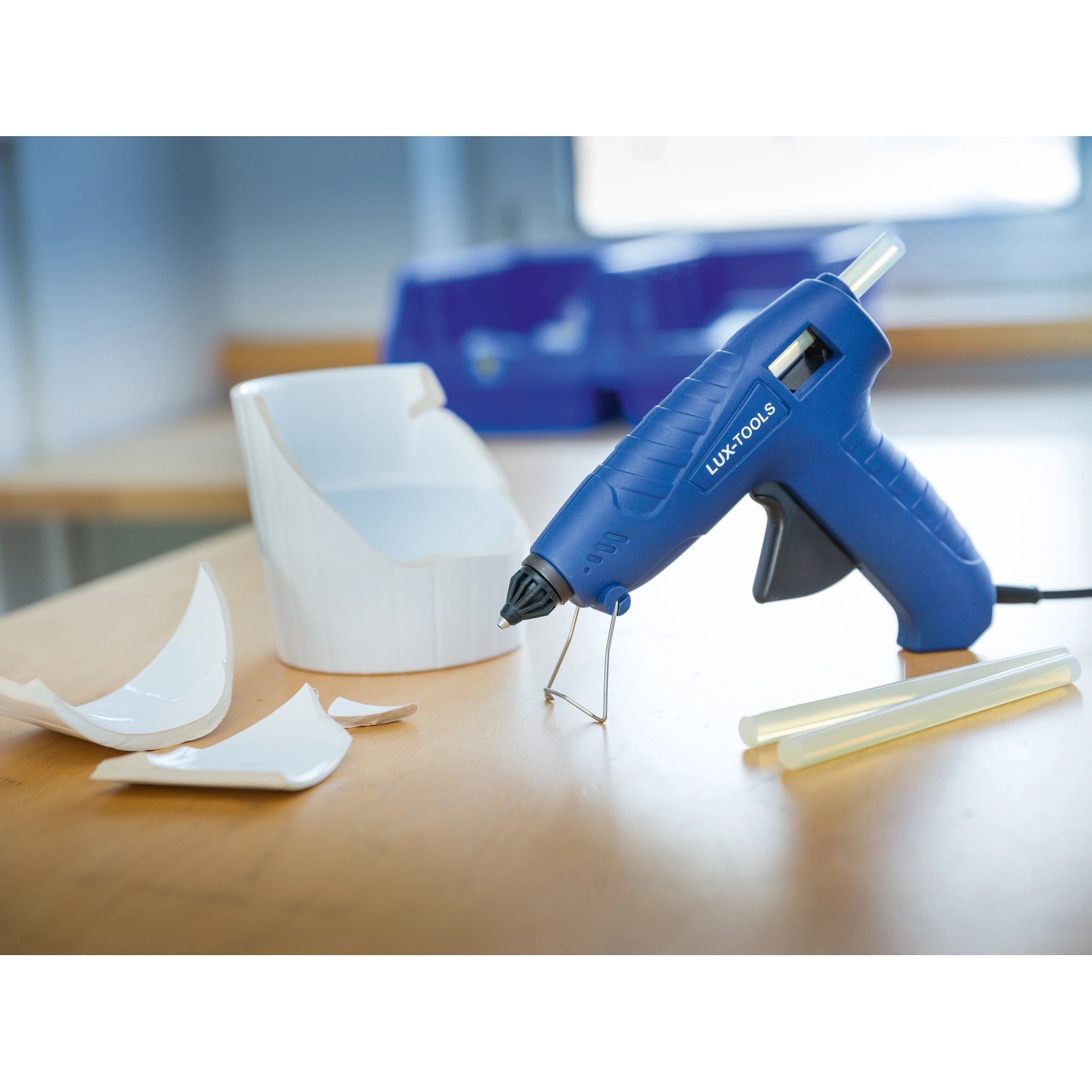 LUX Heißklebepistole 100W Set mit Klebesticks und abgebrochenem Keramikteil auf Tisch.