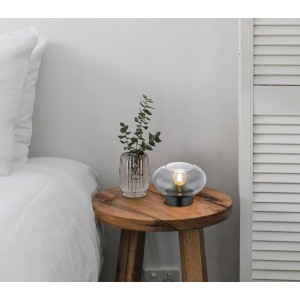 Globo Design-Tischlampe Shaun, schwarz matt mit Rauchglas, auf Nachttisch mit Deko.