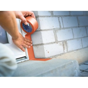Person verklebt orangefarbenes LUX-TOOLS PVC Band 50 mm an Mauer und Fensterrahmen. Robustes Reparaturband für Bau.