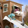 Axi Max Spielhaus mit Rutsche: Holzhaus in Braun-Grün mit spielenden Kindern.
