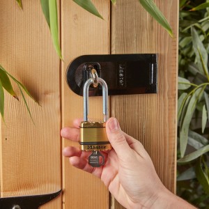 Master Lock Excell Vorhängeschloss aus Messing mit Schlüssel an Holztür.