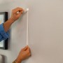 Anwendung der Tesa Powerstrips Click-Small Klebenägel zur Befestigung eines Bilderrahmens an der Wand.
