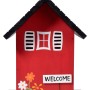 Rotes Dobar Vogelhaus Ambiente mit schwarzem Dach, Blumen und "Welcome" Schild. FSC®-zertifiziert.