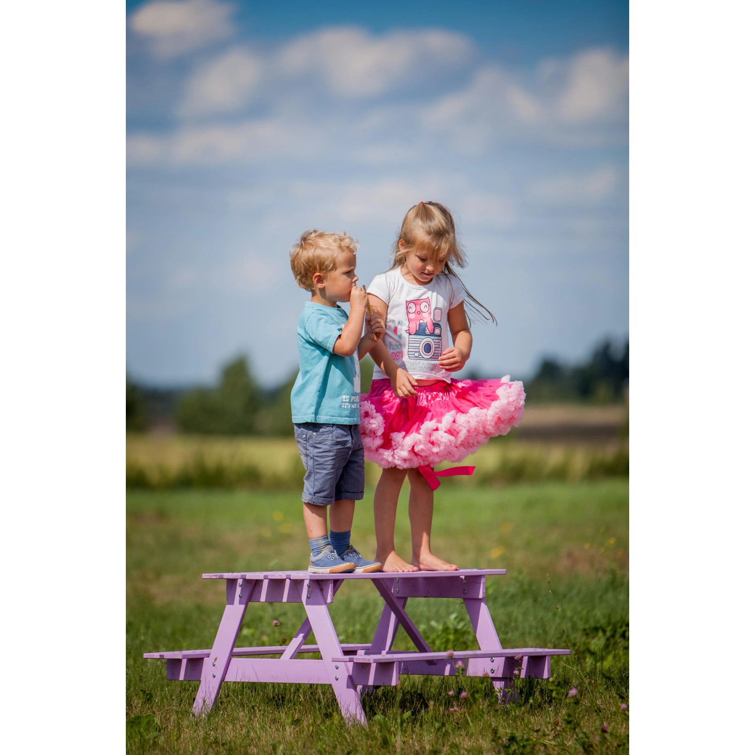Kinder sitzen auf lila Timbela Kindersitzgarnitur Holz M018-1 Groß im Garten.