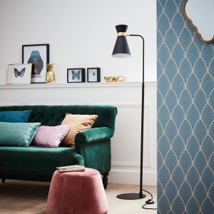 Schwarze Brilliant Standleuchte Goldy mit goldenem Detail neben grünem Sofa.