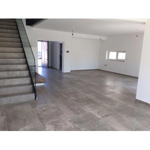 Verlegtes, graues Feinsteinzeug (60x120) im Wohnraum. Moderne Bodenfliese mit Zement-Optik.