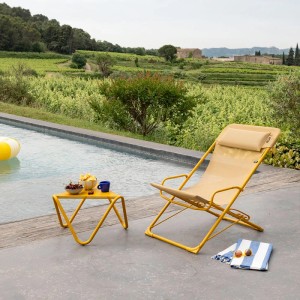 TRANSASWING Batyline® CB Miel Gartenstuhl mit Beistelltisch und Pool im Hintergrund.