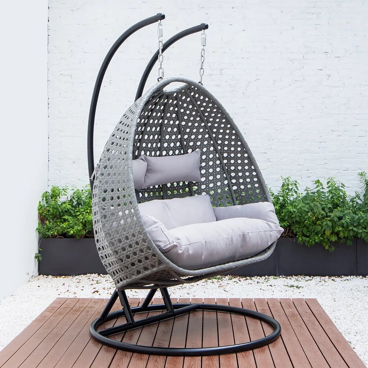 Grauer Home Deluxe Hängesessel Twin aus Polyrattan mit Regenabdeckung und Kissen.