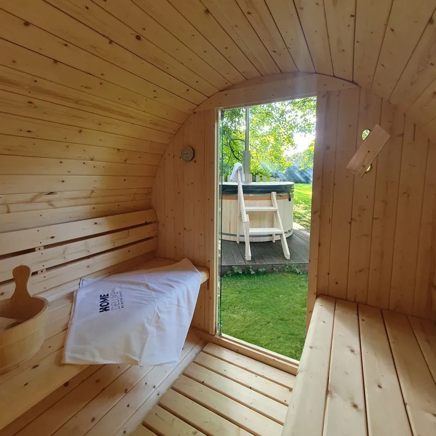 Innenansicht Home Deluxe Fasssauna Lahti Deluxe XL mit 8 kW Ofen, Blick nach draußen auf einen Badezuber.