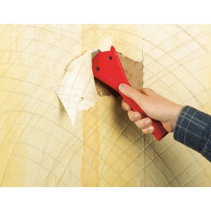 LUX Tapetenentferner im Einsatz: Roter Griff, schräge Klinge entfernt Tapete von der Wand.