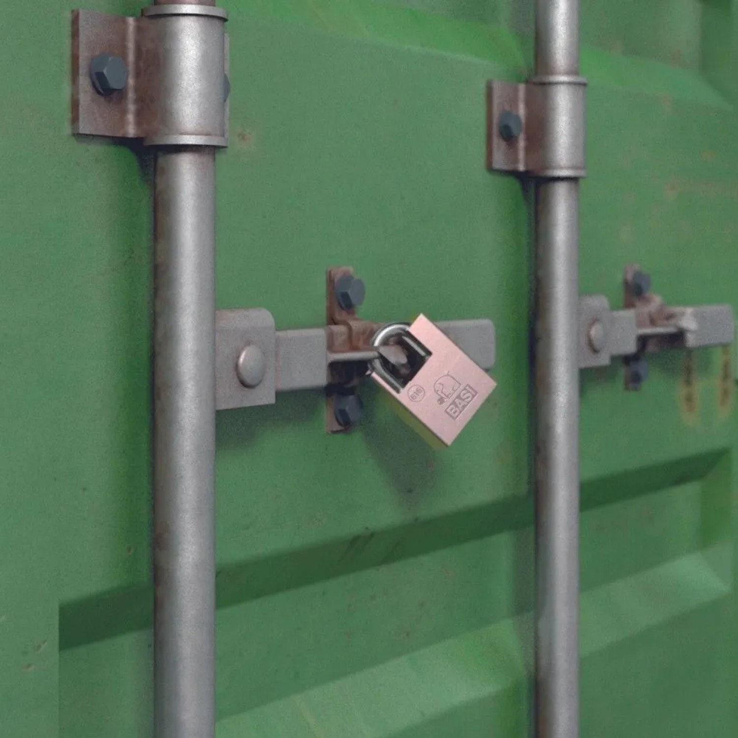 Kupferfarbenes Basi Vorhangschloss mit Bügelschutz an grünem Container. Robustes Stahlgehäuse für sichere Verriegelung.