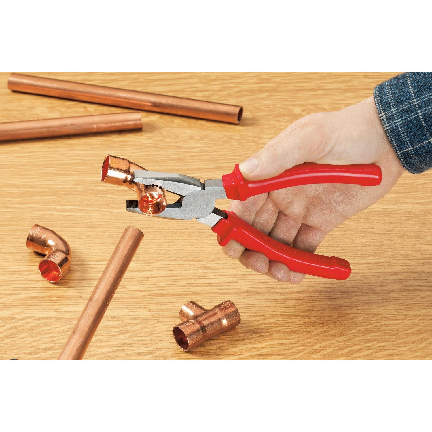 Ellix Zangen-Satz, 3-teilig in Nutzung: Kombizange mit Kupferrohr auf Holztisch.