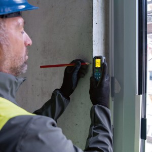 Handwerker misst mit Bosch Professional Laser-Entfernungsmesser GLM 50-25 G an einer Betonwand.