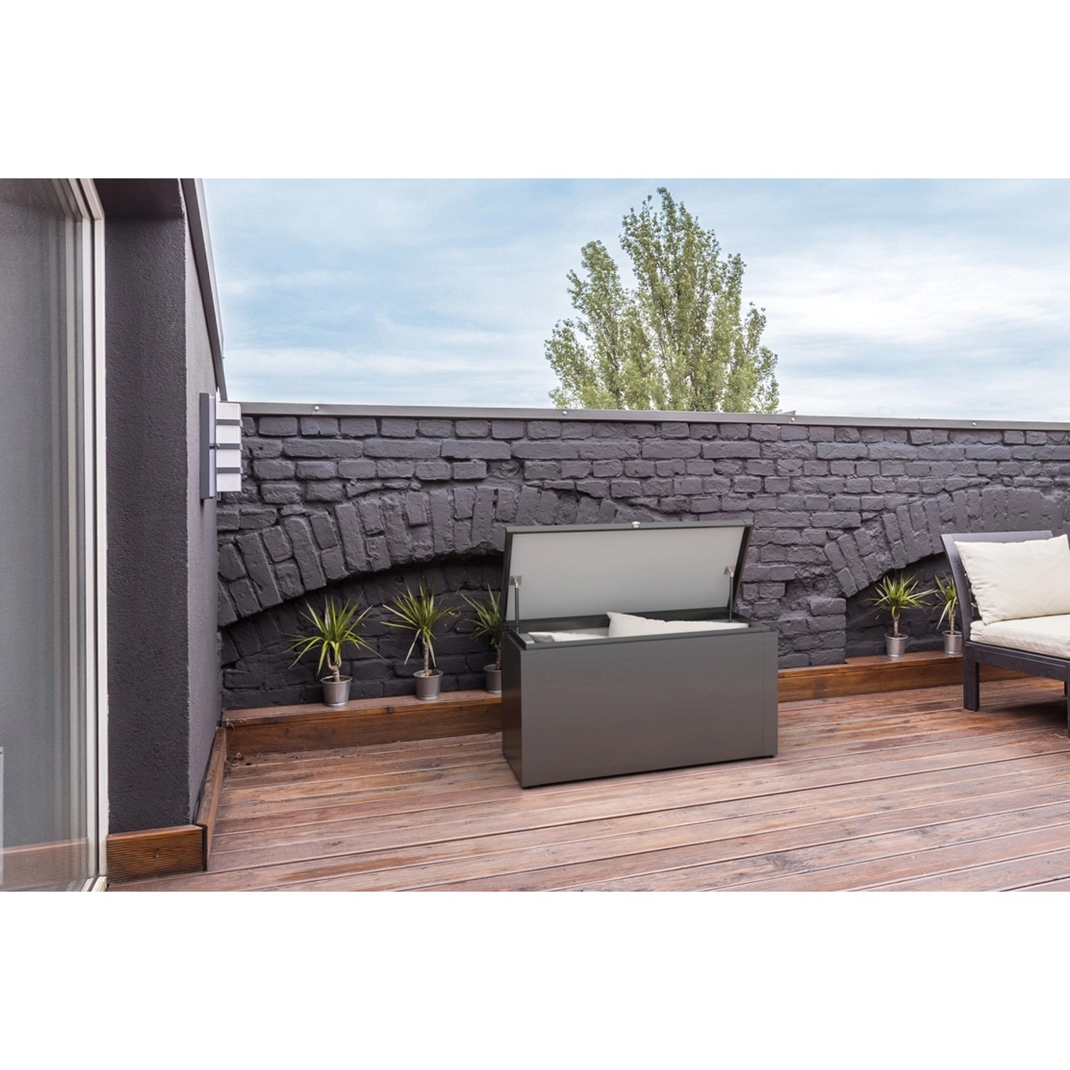 Geöffnete, anthrazitfarbene Guardi Gartenbox (129 cm) auf einer Terrasse. Ideal zur Aufbewahrung von Gartenutensilien.