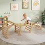 Kleinkind klettert auf hellem Holzklettergerüst mit Bogen und Plattform. Vielseitiges Indoor-Spielgerät für Kinder.