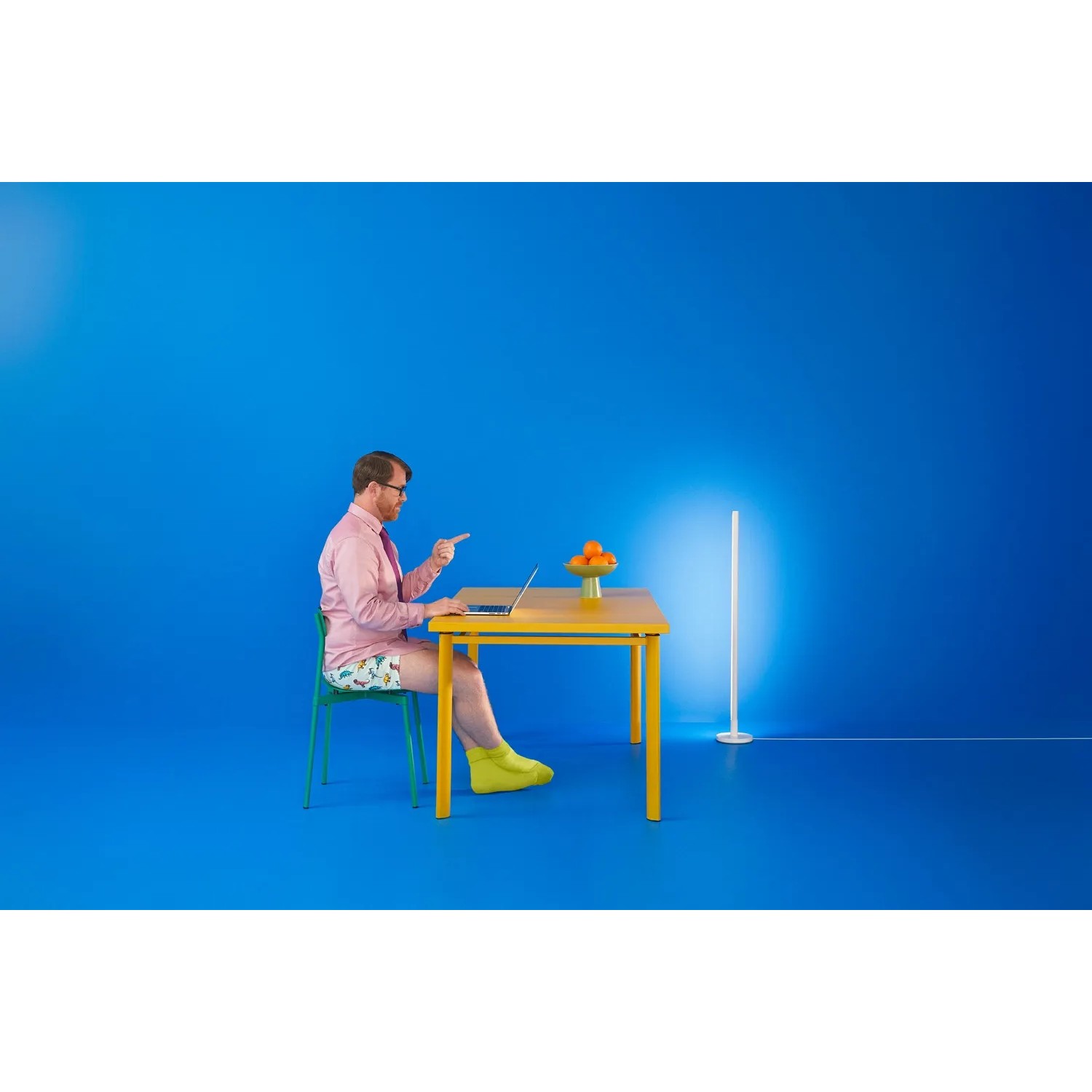 Smarte WiZ LED Stehleuchte Pole, tunable white & color, neben Schreibtisch mit Person.
