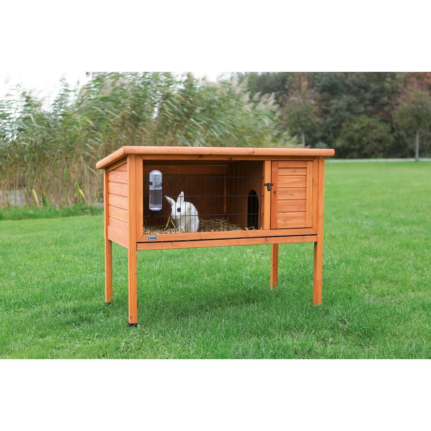 Brauner Trixie Kleintierstall Natura aus Holz mit weißem Kaninchen im Freien.