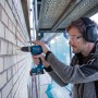 Mann bohrt mit Bosch Professional Akku-Schlagbohrschrauber GSB 18V-45 in Mauerwerk.