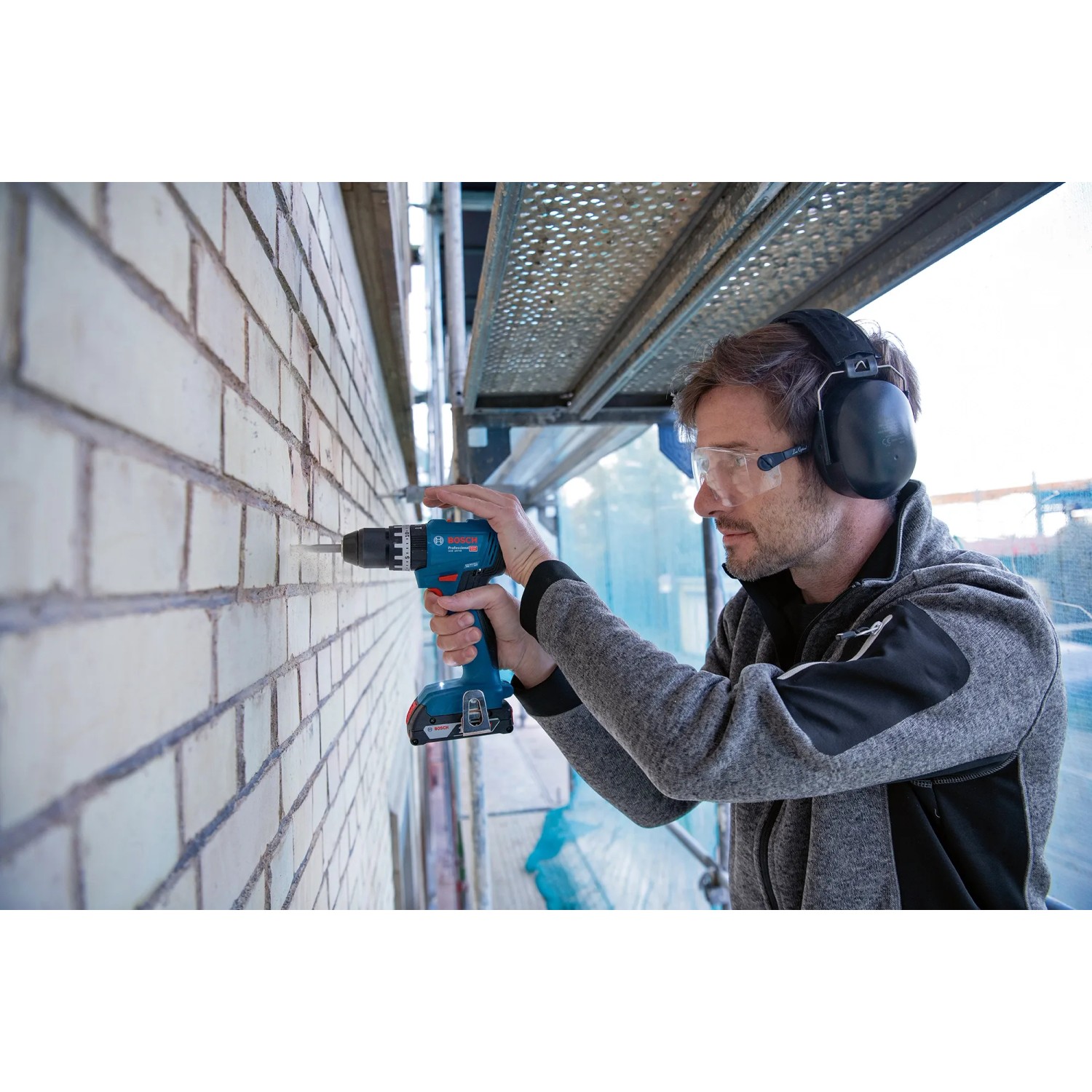Mann bohrt mit Bosch Professional Akku-Schlagbohrschrauber GSB 18V-45 in Mauerwerk.