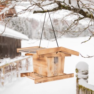Windhager Vogelfuttersilo Canteen XL aus dunklem Holz, hängend im winterlichen Garten.