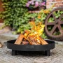 Schwarze CookKing Feuerschale Tunis Ø 60cm mit brennendem Holz im Garten.
