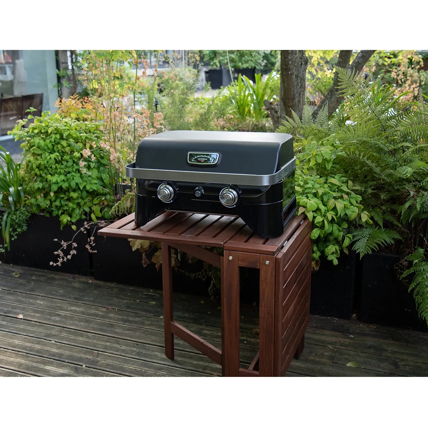 Campingaz Gas-Tischgrill Attitude 2100 LX auf Holztisch im Garten.