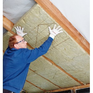 Mann montiert Rockwool Klemmrock Dämmwolle (120mm) zwischen Dachsparren.