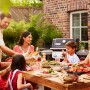 Weber Gasgrill E-210 Spirit (Schwarz) mit Familie beim Grillen im Garten.
