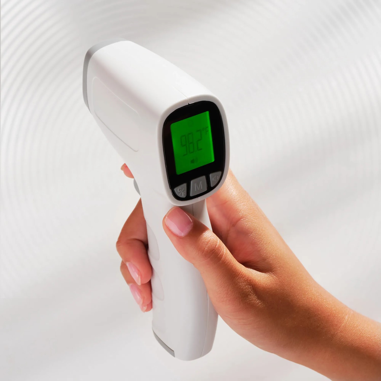 Hand hält ein digitales Infrarot-Thermometer mit grünem Display.