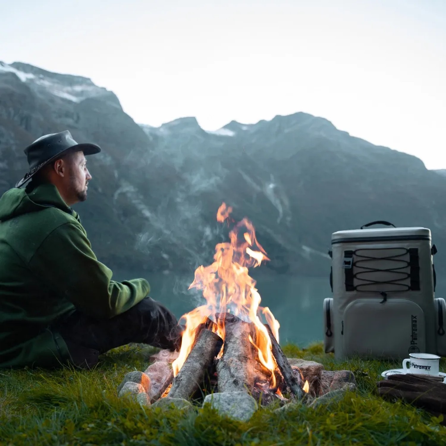 Petromax Kühlrucksack 7 l Grau neben Lagerfeuer in der Natur. Ideal für Outdoor-Abenteuer.