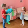 Junge hält blaue Westmann Pool Buddy Schildkröte, Mädchen freut sich im Kinderzimmer.