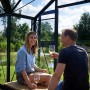 Juliana Gewächshaus Orangerie 15 in Schwarz-Anthrazit: Paar entspannt mit Wein im Gewächshaus.