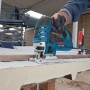 Handwerker sägt mit blauer Bosch Professional Stichsäge GST 150 CE eine dicke Platte. 780 W Leistung für präzise Kurvenschnitte.