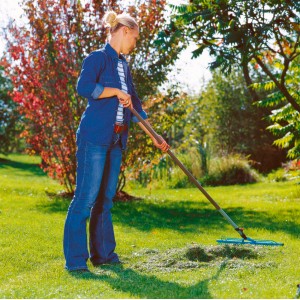 Frau rechen Rasen mit Gardena combisystem-Rasenrechen 60 cm im Garten.