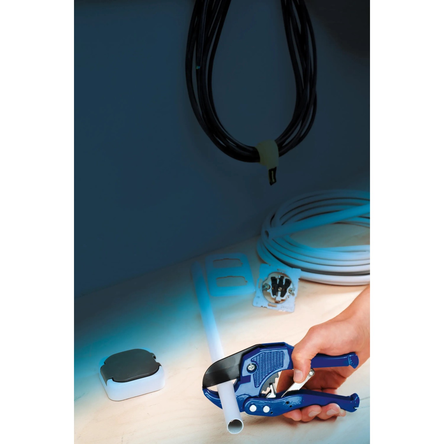 LUX PVC Rohrabschneider 42 mm Classic schneidet ein Rohr. Werkzeug mit blauen Griffen.