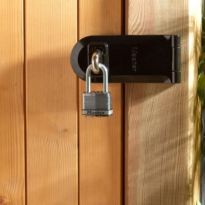 Master Lock Excell Vorhängeschloss an einem schwarzen Riegel an einer Holztür.