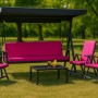 Hollywoodschaukel-Set mit rosefarbenen Kissen, Gartentisch und Stühlen im Grünen.
