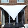 Weißes Floracord Dreiecksonnensegel (460x460x460 cm) spendet Schatten auf Terrasse mit Tisch und Stühlen.
