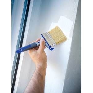 Hand streicht mit LUX Flachpinsel 80 mm Dispersionsfarbe an eine Wand. Pinsel mit Eimerhaken.
