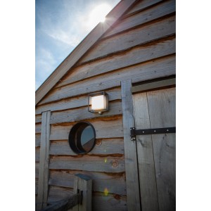 Quadratische Lutec LED Solar-Wandleuchte Curtis mit Bewegungsmelder an Holzwand.