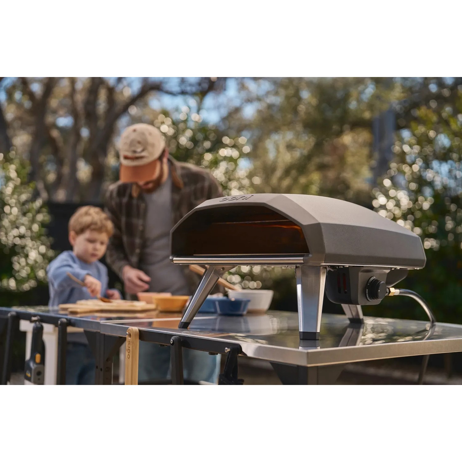Ooni Koda 2 Gas-Pizzaofen (2. Generation) in Schwarzgrau mit Familie beim Pizzabacken.