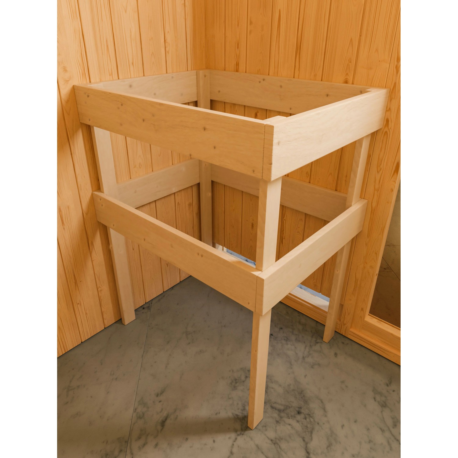 Sauna Antonia im Aufbau: Holzrahmen mit zwei Bänken, Teil einer Massivholzsauna mit Ofen und Glastür.