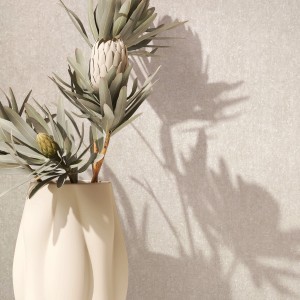 Marburg Vliestapete Betonoptik creme-beige mit Protea-Blüten in Vase vor der Tapete.