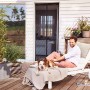 Mann entspannt mit Hund auf Terrasse, geschützt durch tesa Magnetvorhang Anthrazit.