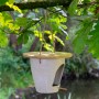 Dobar Vogelfutterspender aus Pflanzenfasern mit Bambusdeckel, hängend an einem Baum.