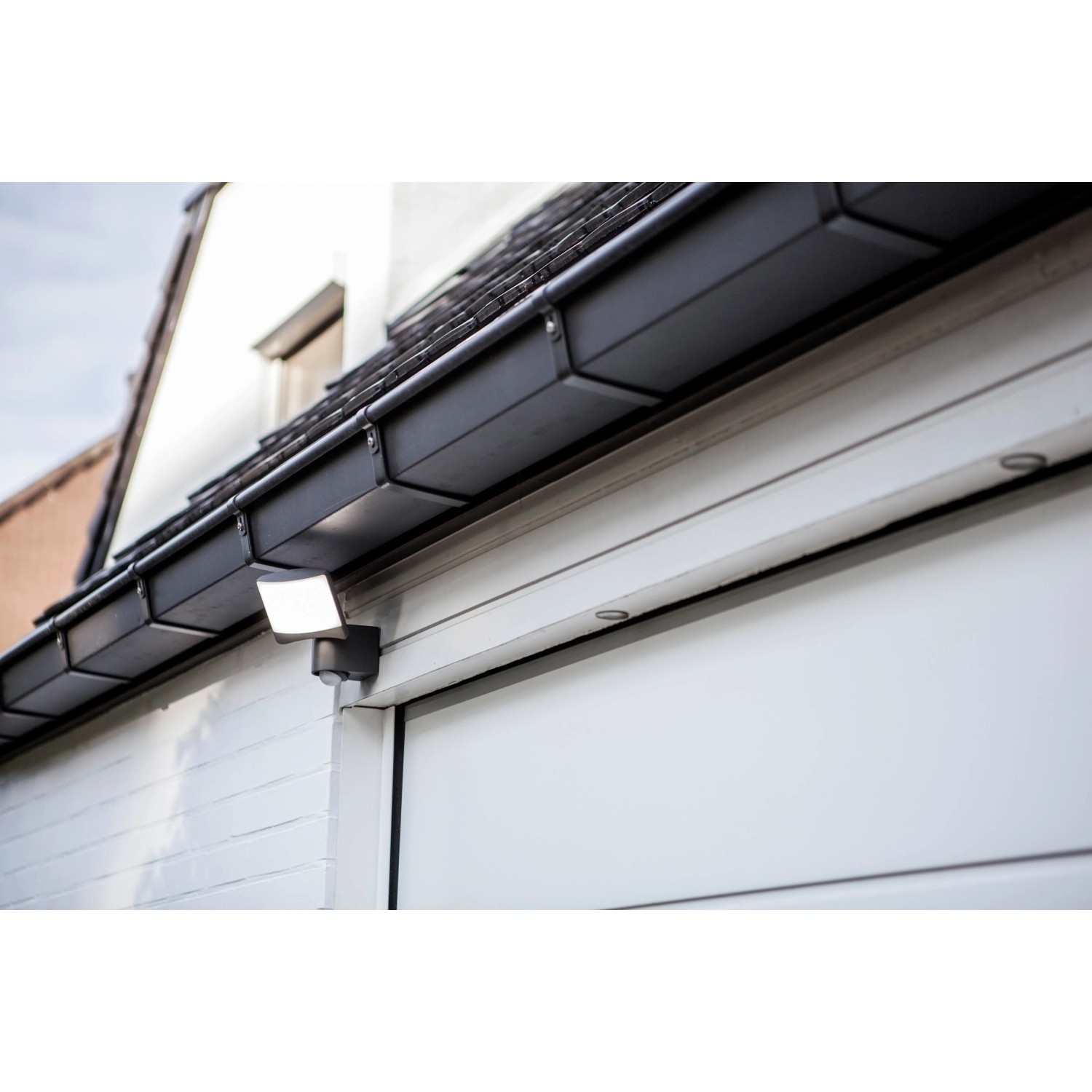 Lutec LED-Außenstrahler Sunshine mit schwenkbarem Kopf an Hauswand montiert.