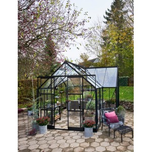 Schwarzes Halls Gewächshaus Garden Room 12,9 m² im Garten mit Pflanzen und Sitzbereich.
